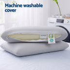 wo pillows with a machine washable cover on a bed next to a washing machine.