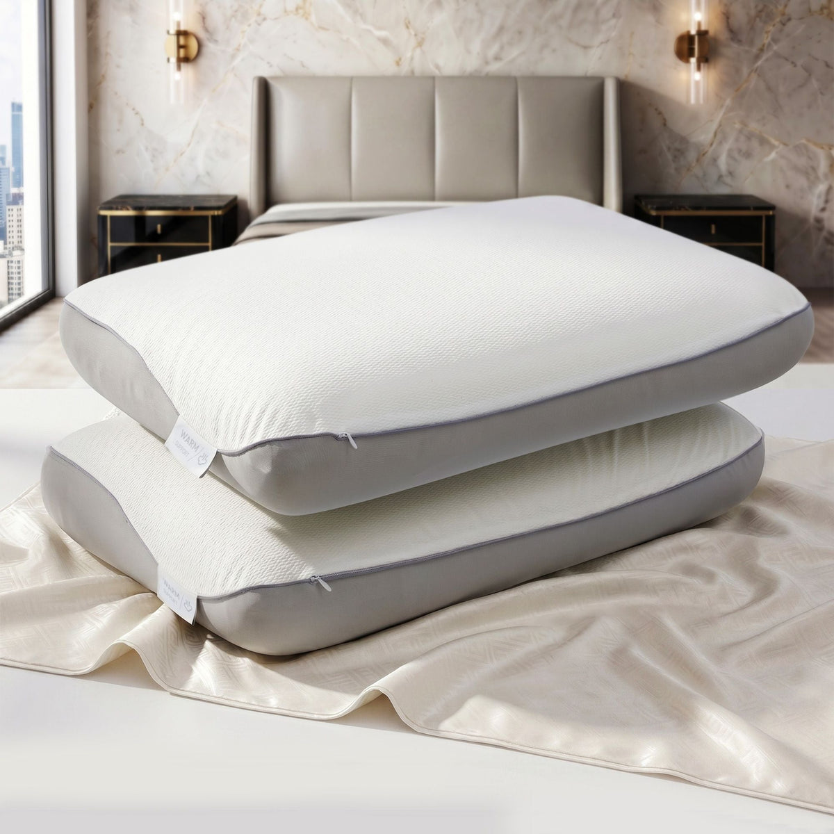 Two white pillows stacked on a bed in a bedroom setting.