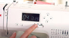 Close-up of a sewing machine with digital display and control panel.
