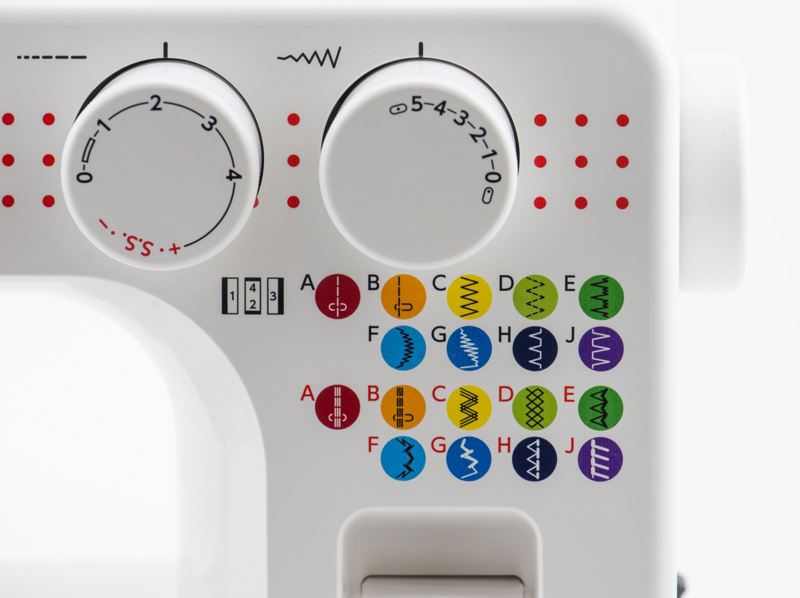 Close-up of a white sewing machine control panel showing two white dials, red dot markings, and a grid of colorful thread type icons labeled A through J.