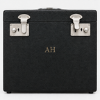 This  black textured hard case with silver metal latches and a gold monogram  comes withis preloved Singer 222k1 feather weight sewing machine. photographed against a light gray background.